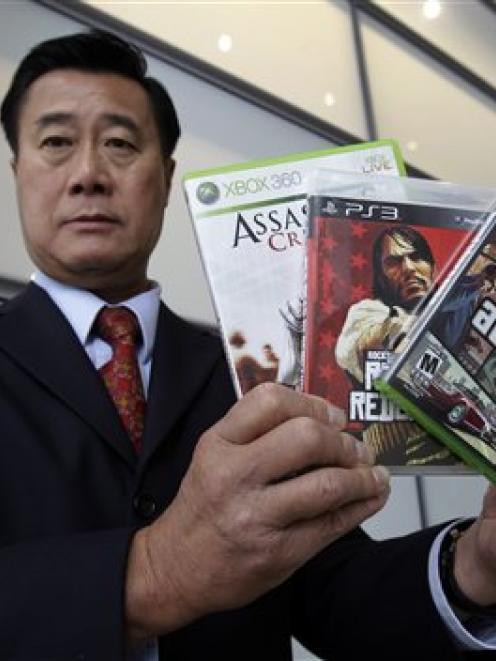 California State Senator Leland Yee, of San Francisco, holds up three video games after a news...