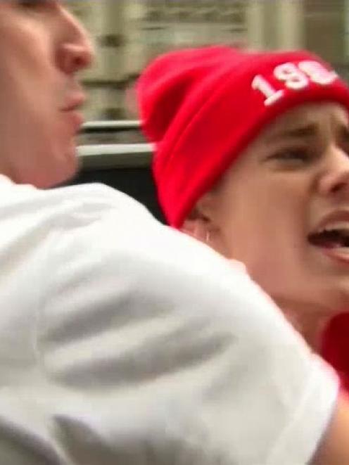 Canadian pop star Justin Bieber is held back by a member of his security team as he confronts a...