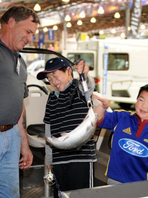 Canterbury Sports Fishing Club's Ray Eade watches as James (10) and Jacob Yee (5) hold a live...