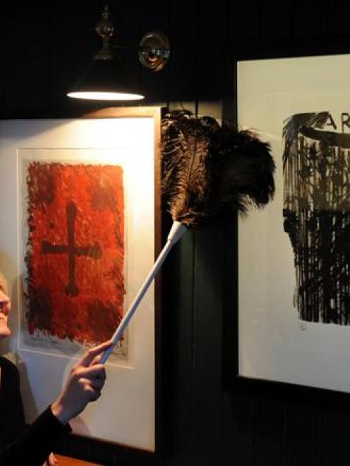 Careys Bay Hotel publican Jo Kidston dusts a Ralph Hotere painting yesterday in preparation for...