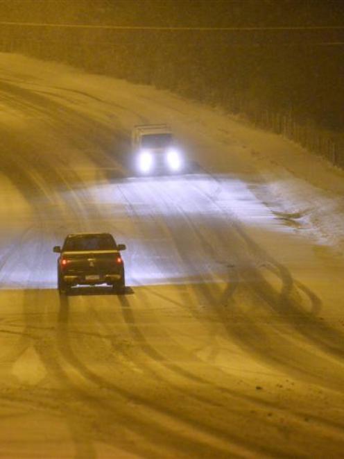 Cars move along Taieri Rd, Dunedin, about 10pm yesterday, as snow continues to fall. Photo by...