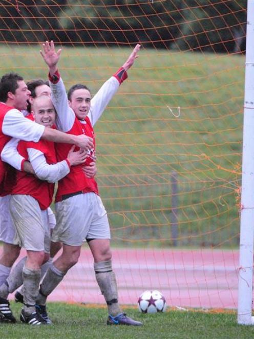 Caversham players mob Tom Jackson (hands raised) after the striker scored the final goal in the 3...