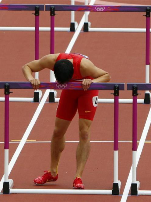 China's Liu Xiang kisses the last hurdle in his lane after crashing into the first hurdle and...