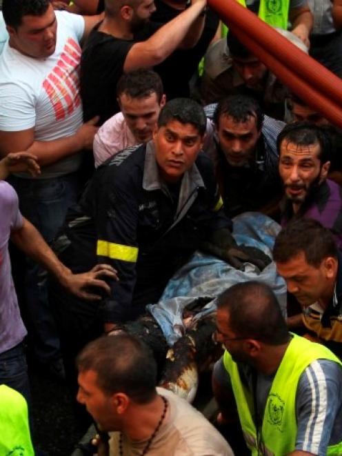 Civil Defence members carry a burnt man on a stretcher at the site of an explosion in a Beirut...