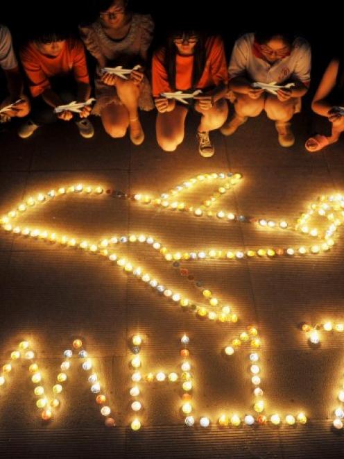 College students gather around candles forming the shape of an airplane, during a candlelit vigil...