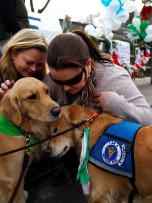 Comfort dogs receive attention from two women near a memorial for the Sandy Hook Elementary...