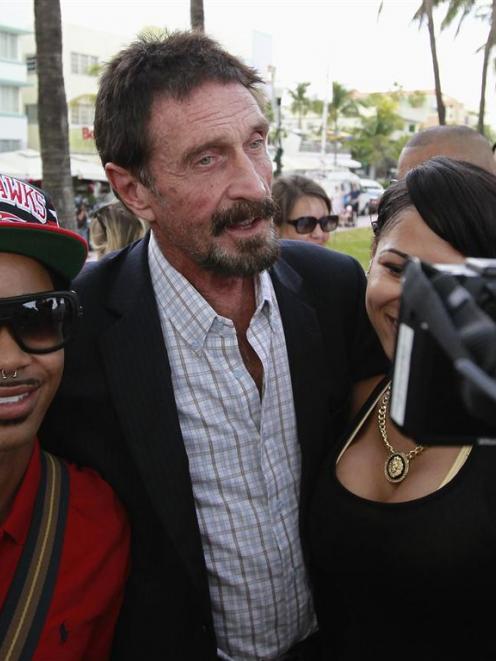 Computer software pioneer John McAfee poses with tourists as he speaks with reporters outside his...