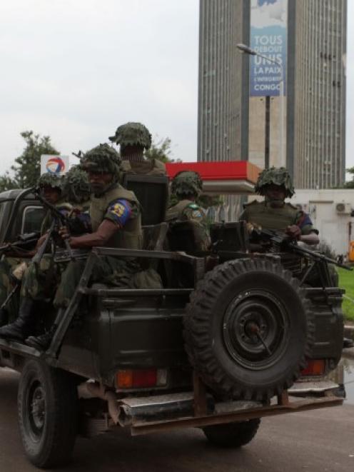 Congolese soldiers ride on their pick-up truck towards the state television headquarters in the...