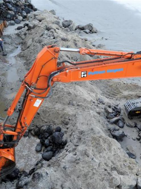 Contractors work on the last section of sheet piling going in in front of the sea wall  to stop...