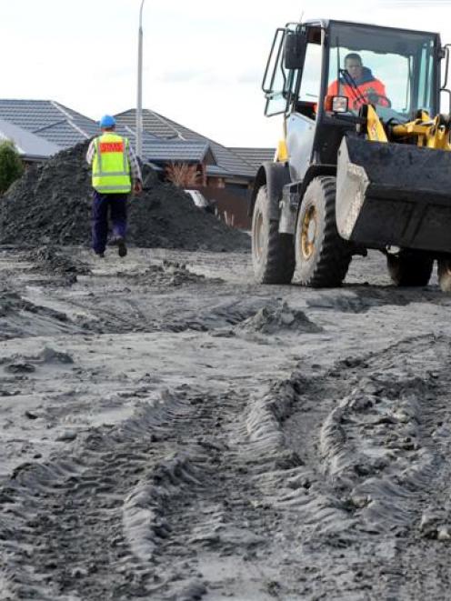 Contractors work to clear a Bexley street of silt yesterday. Photo by Craig Baxter.