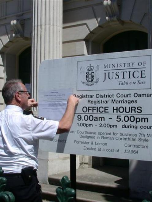 Court security officer Wayne Olsen yesterday puts up notices closing the Oamaru Courthouse...