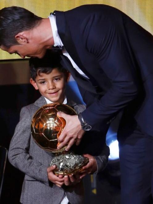 Cristiano Ronaldo holds the trophy with his son, Cristiano Ronaldo Jr, after winning the FIFA...