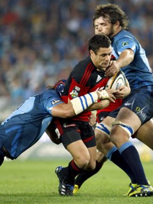 Crusaders first-five Daniel Carter, center, is tackled by Bulls captain Victor Matfield, left,...