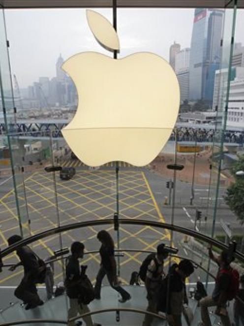 Customers walk past a huge Apple logo at the new store which is located on two floors linked by a...