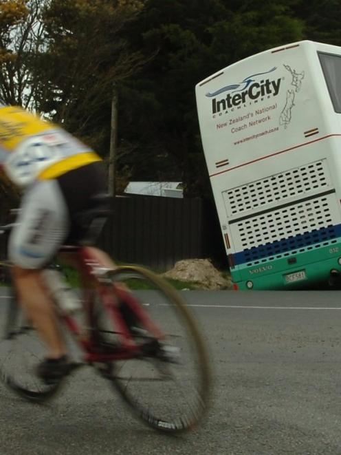 Cyclists competing in the Otago junior cycling championships pass an Intercity bus which slipped...