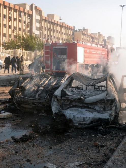 Damaged cars are seen at the site where two explosions rocked the University of Aleppo, killing...