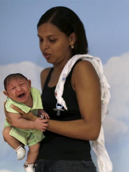 Daniele Ferreira holds her son Juan Pedro during a session this week to stimulate the development...