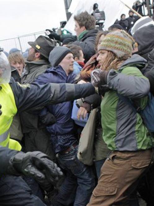 Danish riot police push back protestors, one bleeding, at right, during a demonstration outside...