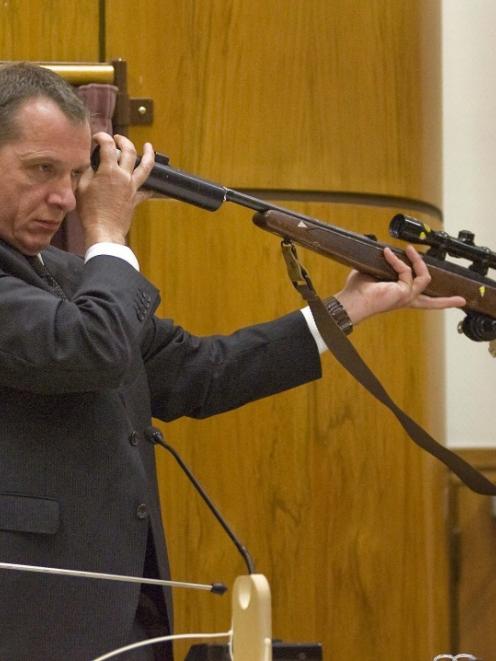 Defence witness Philip Boyce holds a rifle as suggested by a previous witness during a...