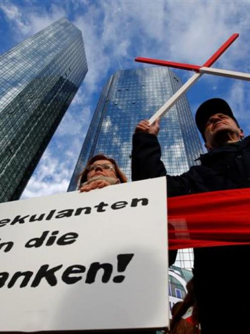Demonstrators hold a placard in front of the headquarters of Germany's largest business bank,...