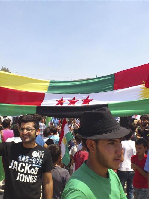 Demonstrators hold Kurdish and Syrian opposition flags during a protest against Syria's President...