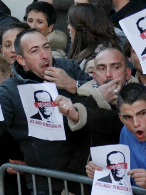 Demonstrators hold papers reading 'Hollande, resignation, go away' while French president...