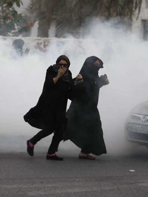 Demonstrators in Bahrain run through a cloud of tear gas fired by police during a protest....