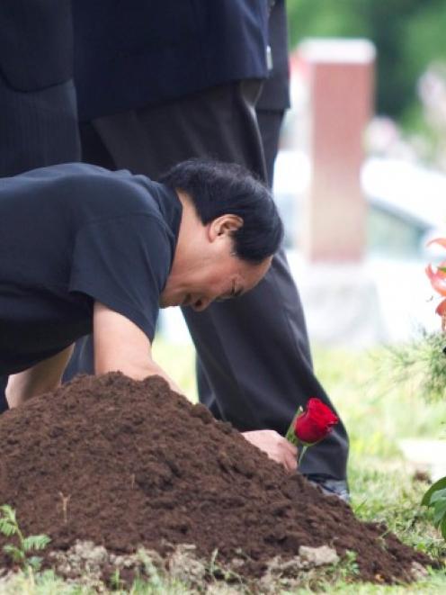 Di Rang Lin, father of slain student Jun Lin lays a rose at his son's gravesite during funeral...