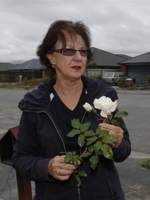 Diane Hale-Fielding   with a rose from the garden of her red-stickered house in Wetlands Grove,...