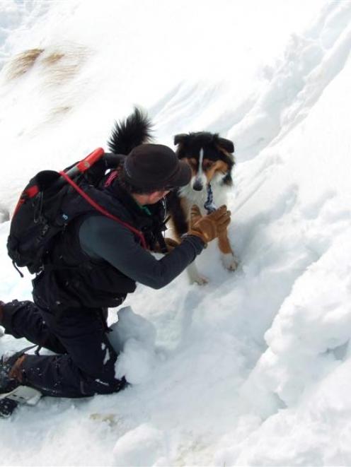 Dog handler Matt Gunn gives commands to his avalanche dog Rocket outside the  snow cave. Photos...