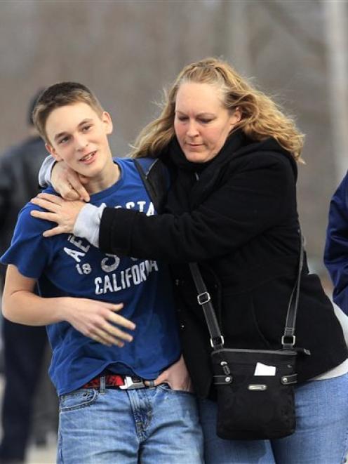 Doug Gasper, a ninth grader at Chardon High School, is hugged by his mother, Sandy, as they leave...
