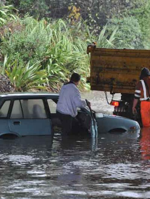 Downer crew assist a motorist to recover a car from under the Burnside overbridge during the flood.