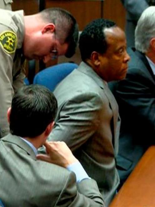 Dr Conrad Murray is handcuffed as he is remanded into custody after the jury returned with a...