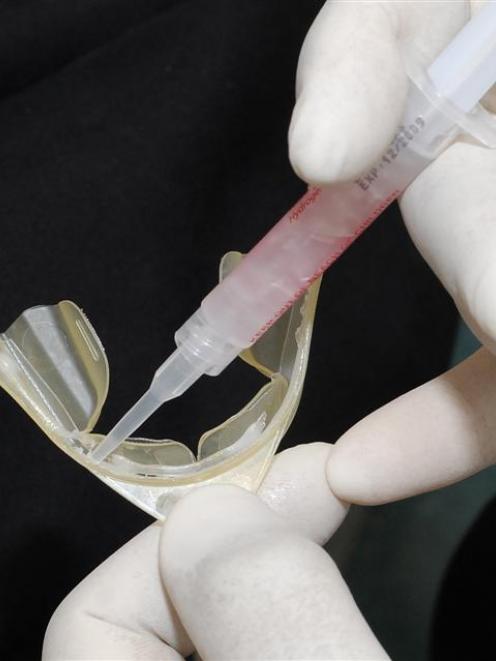 Dr Ray George demonstrates how to apply gel to a mouthguard.  Photo by Gregor Richardson.