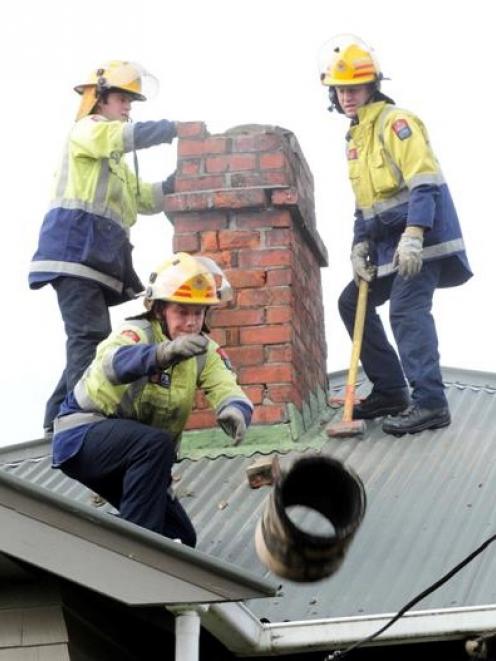 Dunedin firefighter Chris Kennett throws a chimney pot off a roof in Avonside yesterday as Simon...