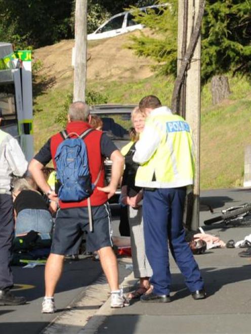 Dunedin police interview a bystander as St John Ambulance staff treat a cyclist (obscured) who...