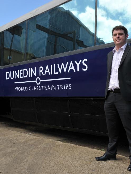 Dunedin Railways business manager Toby Mann in front of a rebranded Taieri Gorge Railway carriage...