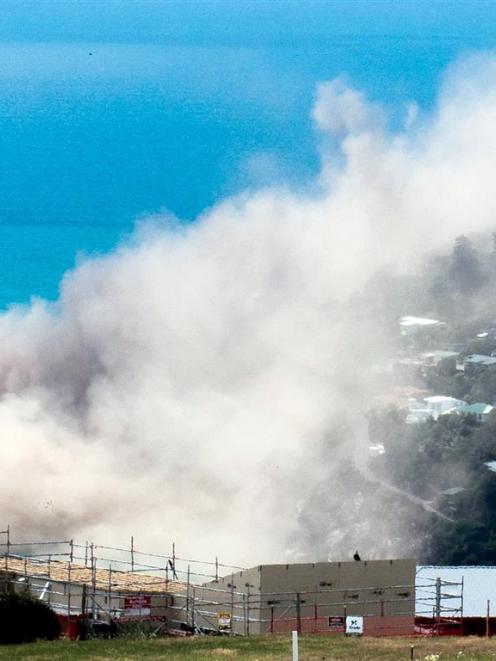Dust and debris rise above houses after a cliff collapsed on the Whitewash Head area, located...