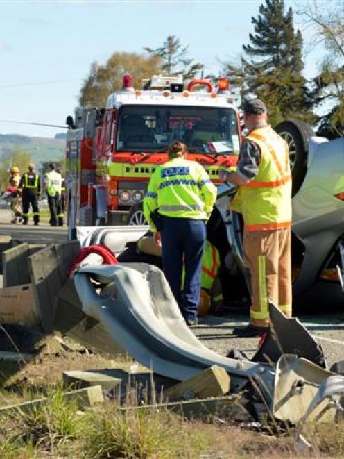 Emergency services inspect a car that overturned on State Highway 1, near Waikouaiti, yesterday....