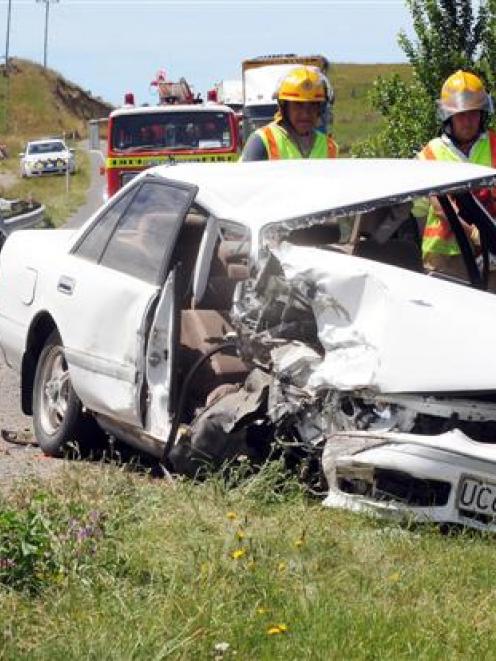 Emergency services personnel survey the scene of a three-car crash near Totara yesterday...