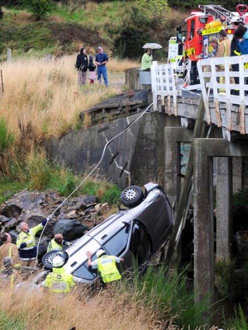 Emergency services work to stabilise a car before helping its driver out, after the vehicle...