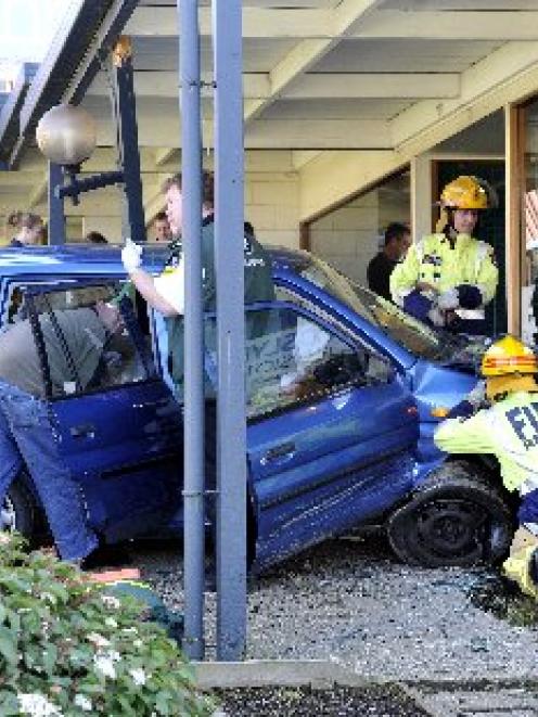 Emergency services workers work to help a woman who was injured when the car she was driving...