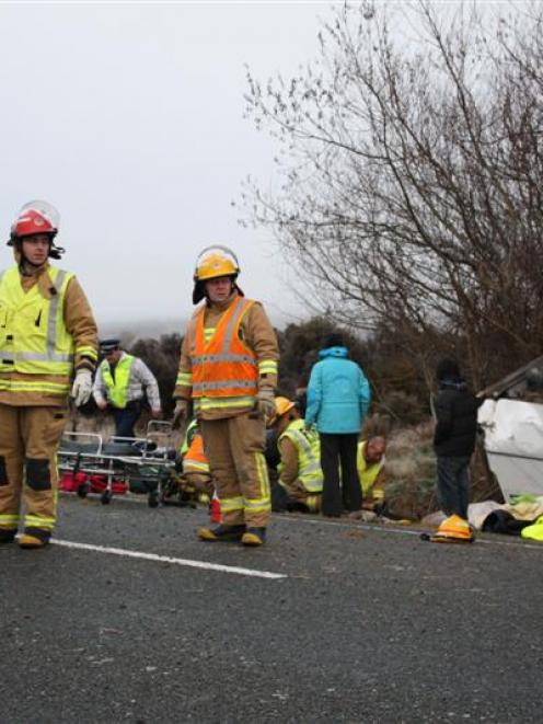 Emergency workers at the scene of a fatal bus crash on the Milford Rd yesterday. Photo by ...