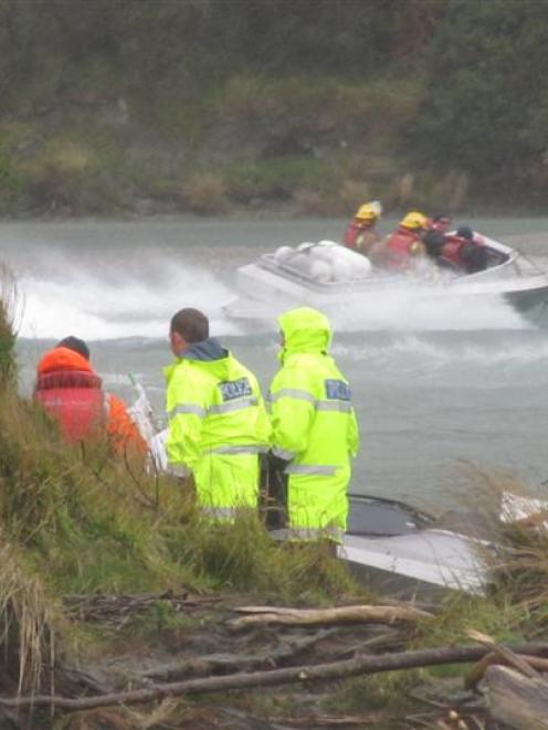 Emergency workers help the crew of a jet-boat which flipped at the confluence of the Shotover and...