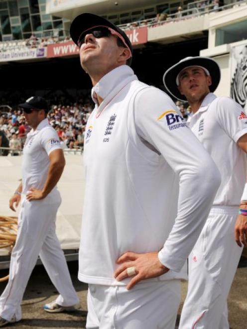 England's Kevin Pietersen (3rd L) and Stuart Broad (4th L) look up as the players prepare to walk...
