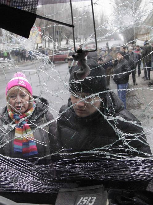 eople look through the front windshield of a damaged trolleybus in Donetsk, January 22, 2015. At...