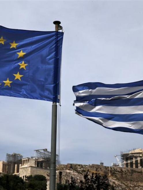 European Union (left) and Greek national flags flutter as the ancient Parthenon temple is seen in...