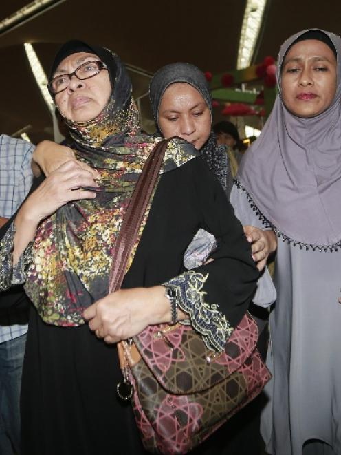 Family members of those onboard the missing Malaysia Airlines flight MH370 walk into the waiting...