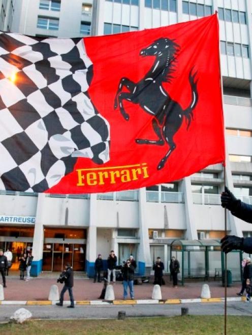 Fans fix a Ferrari flag in the ground in front of the CHU Nord hospital in Grenoble where Michael...