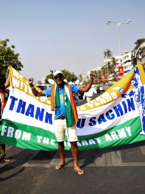 Fans stop traffic while holding a banner in tribute to Sachin Tendulkar outside a stadium in...